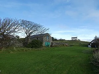 Stone buildings, grass and bare-branched trees in Cregneash on the Isle of Man.