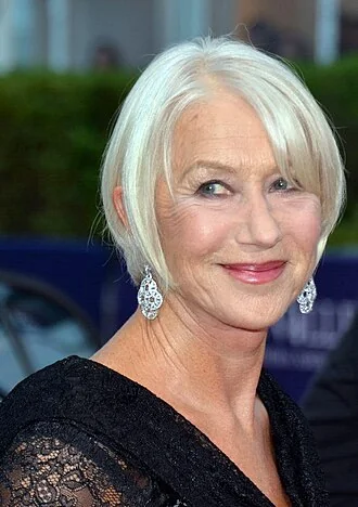 Helen Mirren with short white hair and a black lace outfit at Deauville in 2014.