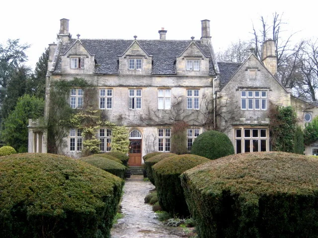 Barnsley House seen beyond clipped hedges and a narrow garden path.