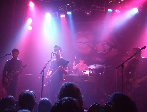 Stereophonics playing on a small stage beneath pink and purple concert lights.