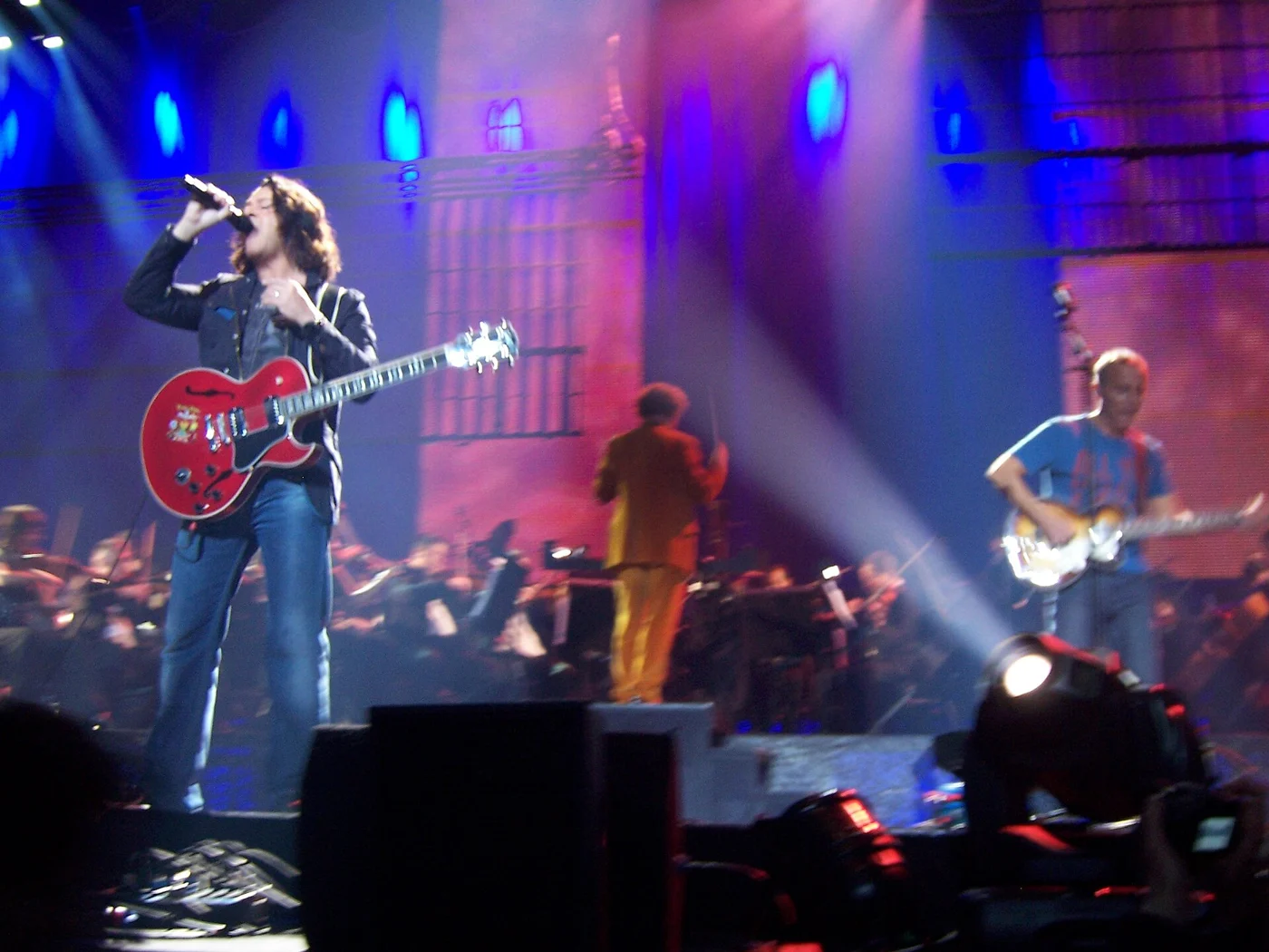 Roland Orzabal and Curt Smith of Tears for Fears performing with guitars under blue stage lights.