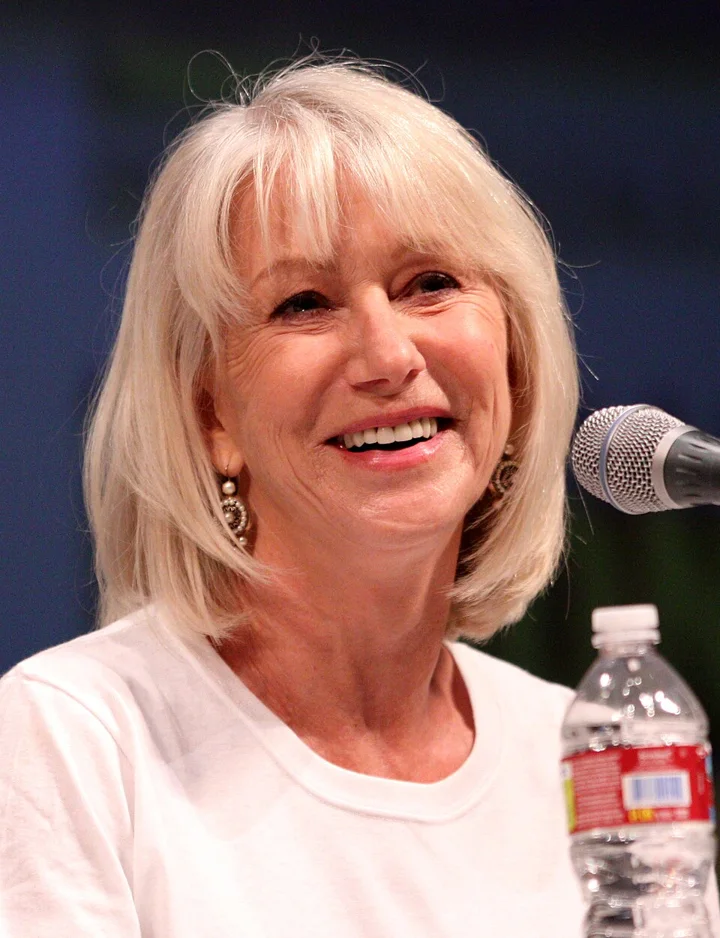 Helen Mirren smiling beside a microphone at San Diego Comic-Con in 2010.